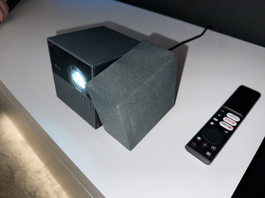 A cube-shaped projector with a rectangular speaker on its side that’s twisted to a different angle.